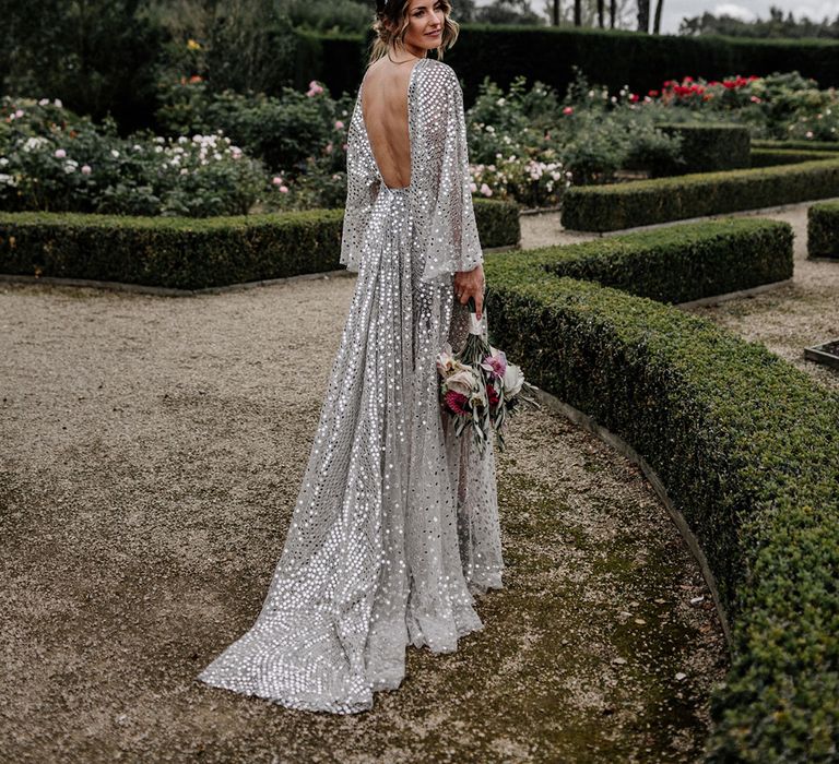 Bride in a sparkly silver wedding dress with low back detail at her outdoor tipi wedding 