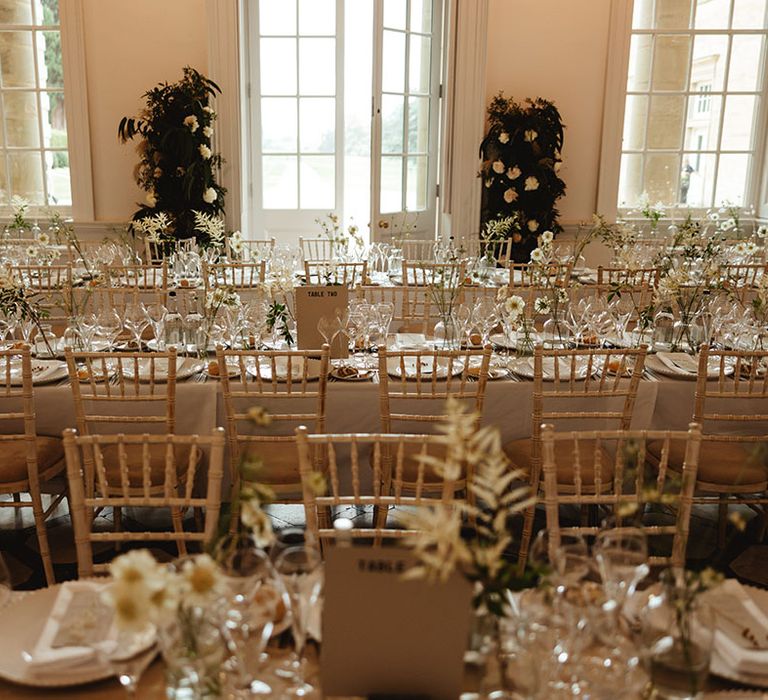 Wedding reception table setting with clean and natural styling including white tablecloths, napkins, plates and flowers