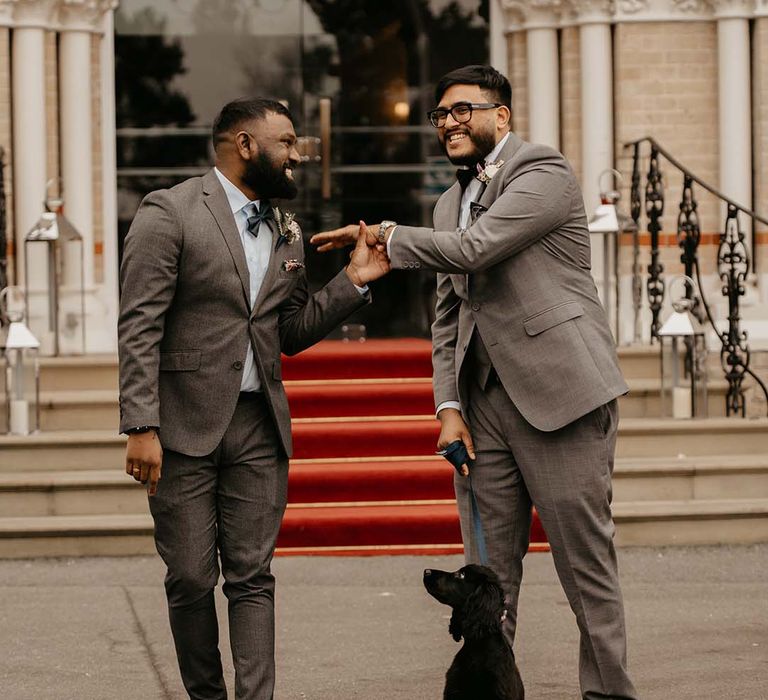 Groom and groomsman in grey suit and bow ties with boutonnières  