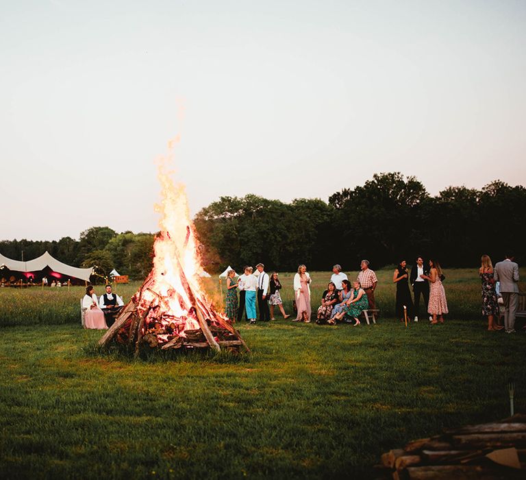 Large bonfire with wedding guests socialising around it