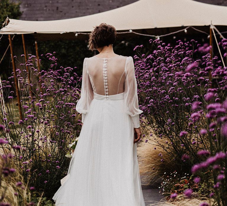 Bride in wedding dress with sheer back and sleeves with button detail and tulle skirt