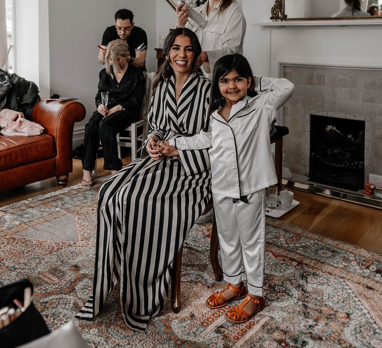 Bride on the wedding morning in a black and white striped robe and flower girl in satin pyjamas 