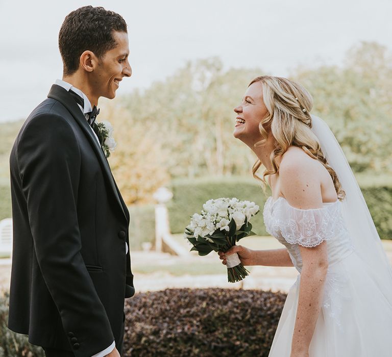 Bride and groom get their first look at each other with groom in black tie and bride in off the shoulder wedding dress