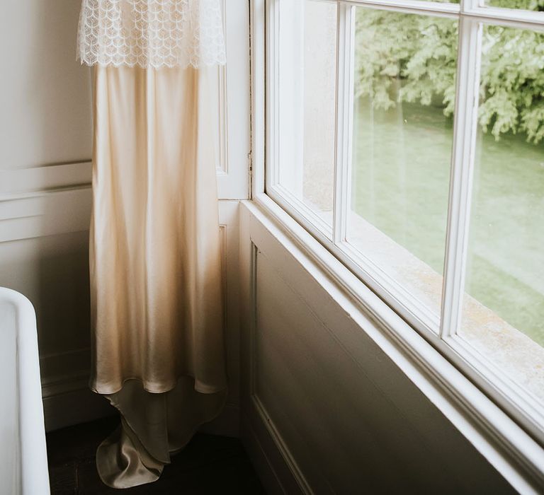 Kate Beaumont bridal gown hangs beside window 