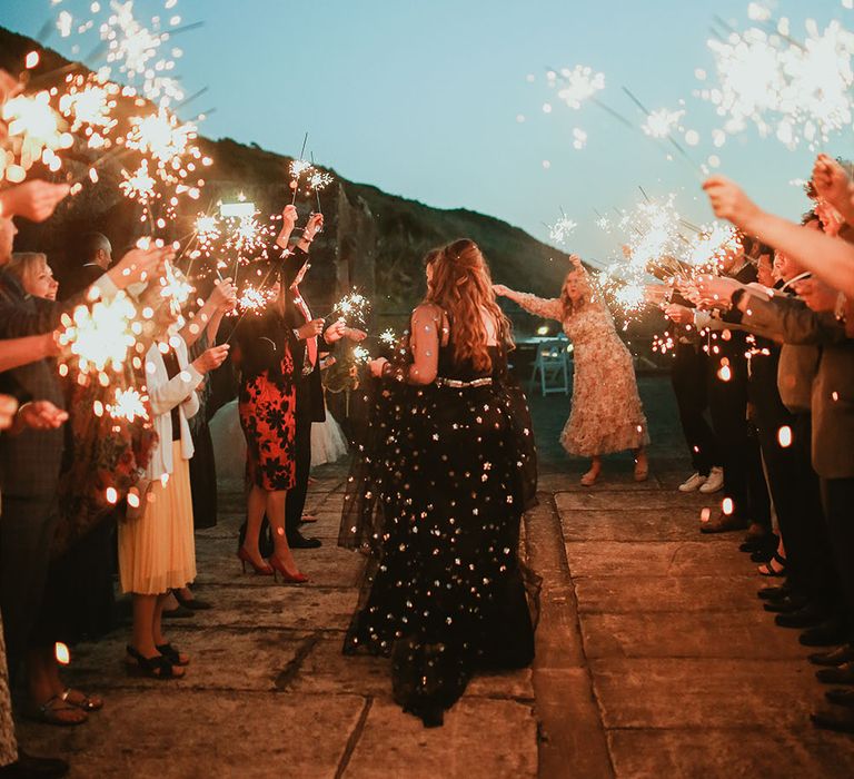 Bride & groom walk through sparkler exit outdoors on their wedding day