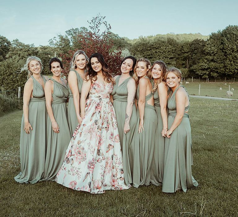 Bridesmaids in green dresses smile with the bride in a hand painted silk wedding dress 