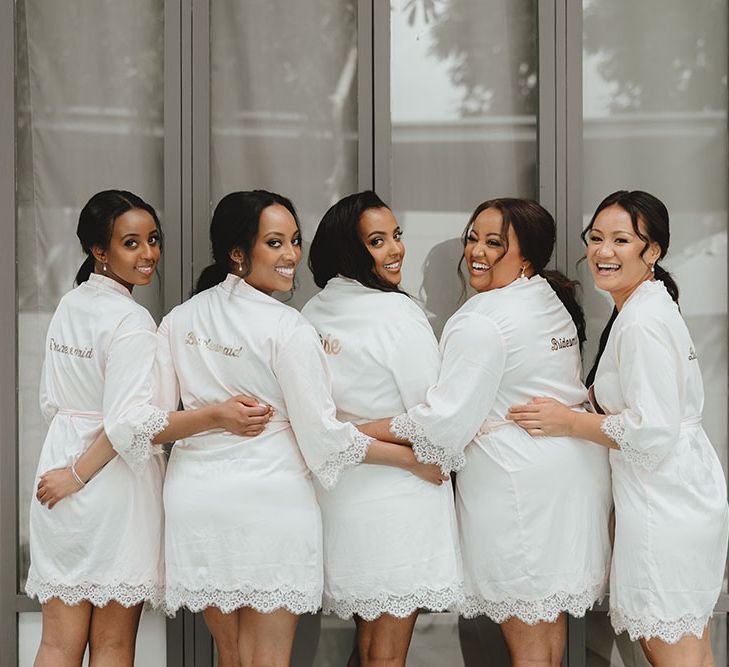 Bride wears matching short dressing gown with her bridesmaids in white and personalised to the back