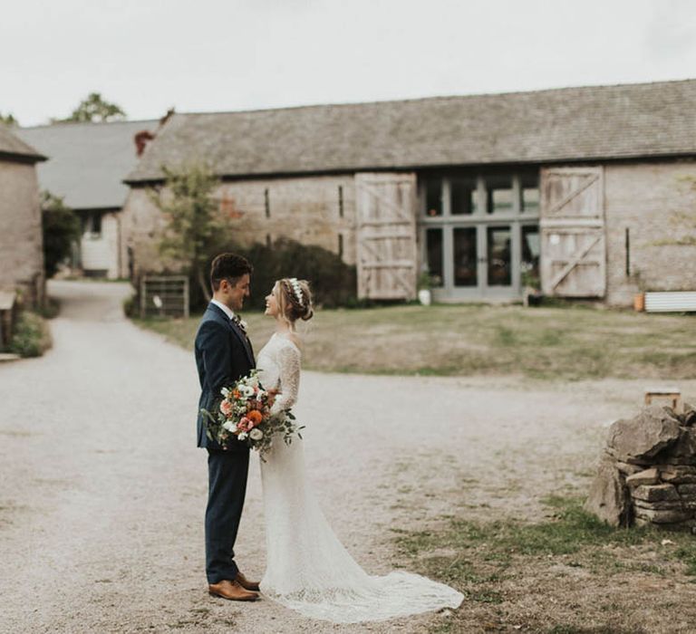 Bride and groom stand staring into each other's eyes for their barn wedding 