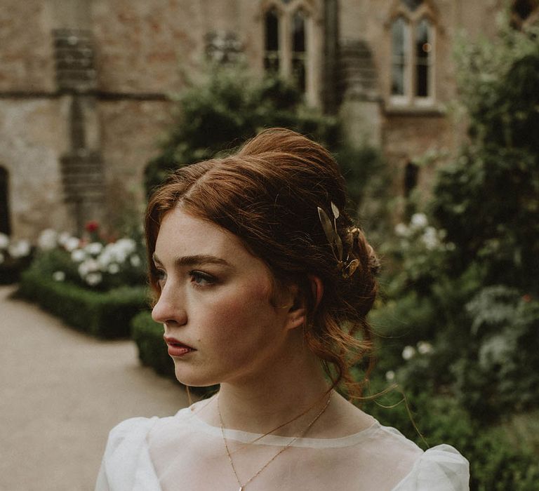 Bride with natural makeup wearing a wedding dress with sheer top layer and delicate gold necklace 