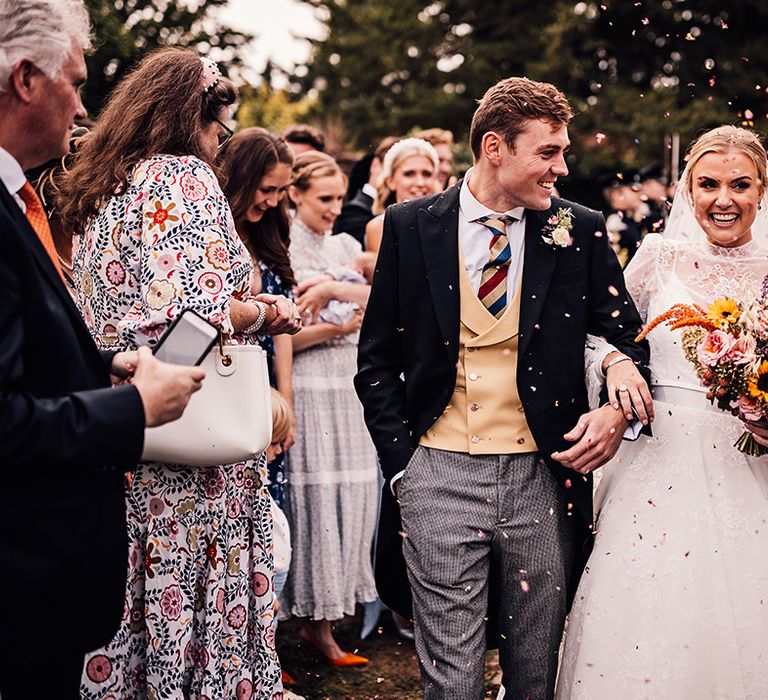 Bride and groom smile widely as they have their confetti moment 