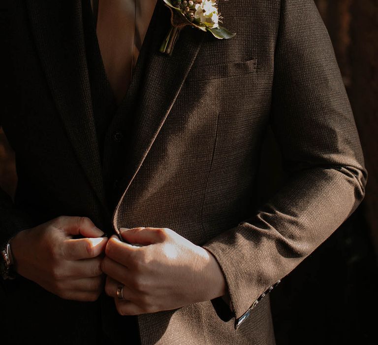 Groom in a brown suit with a satin tie and pink rose buttonhole