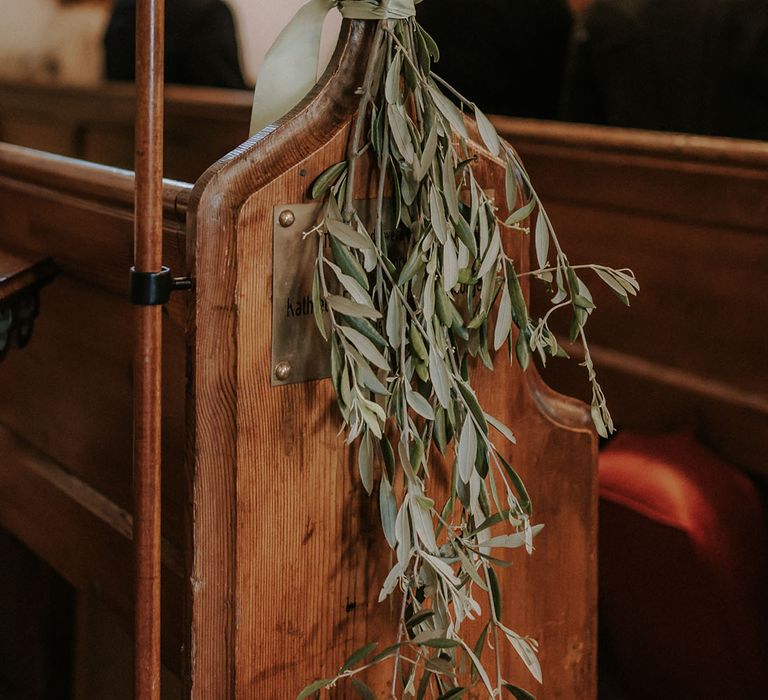 Pretty greenery lines the pews and aisle at the church wedding ceremony 