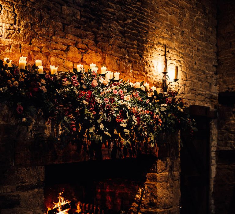 Cripps Barn wedding venue with a roaring fire and soft candlelight with pretty pink flowers