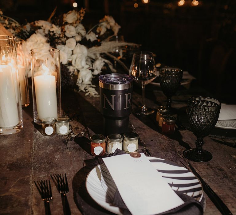 White pillar candles and black napkins on rustic wooden table for modern styled jungle tablescape 