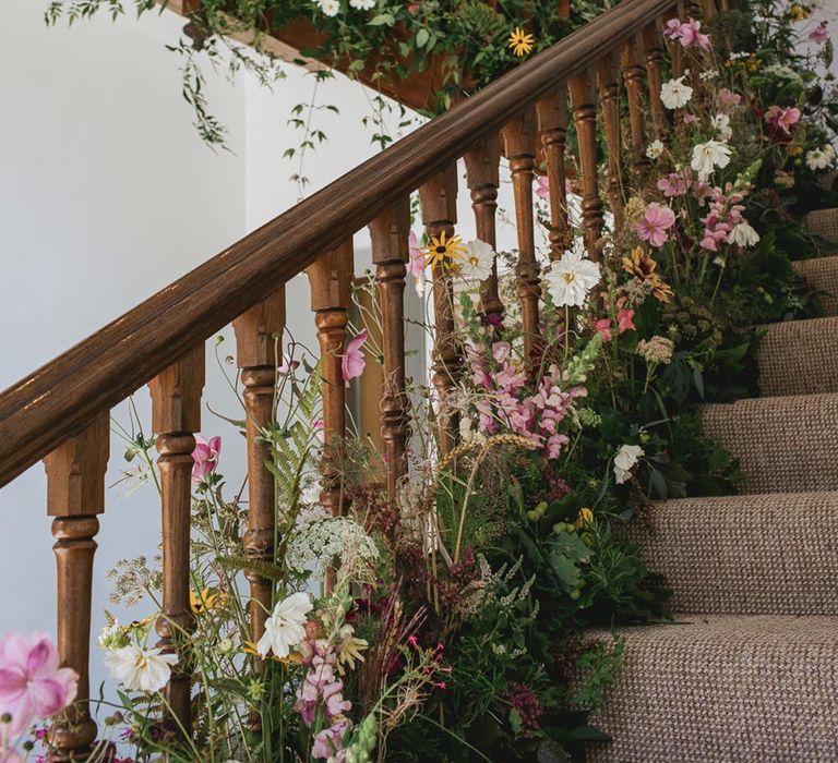 Pink, white, and yellow wedding wildflowers decorating the staircase 