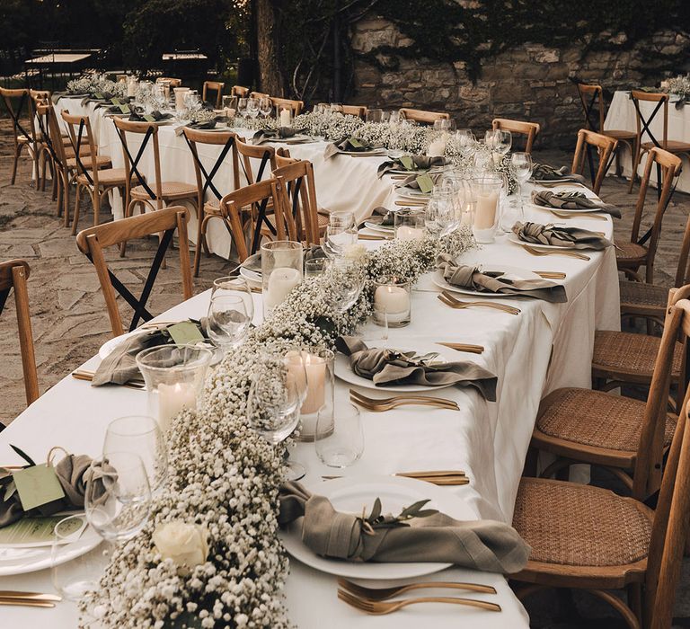 Winding reception tables covered in white tablecloths complete with babys breath table runner and fabric napkins 