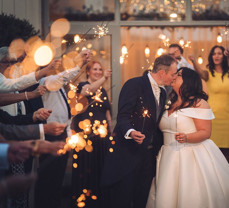 The bride and groom share a special kiss as they have a sparkler send off and all the guests join in waving sparklers 