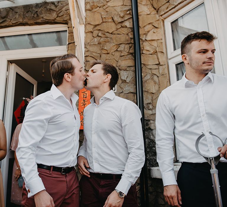 Groom and his groomsmen play traditional door games outdoors before wedding ceremony 