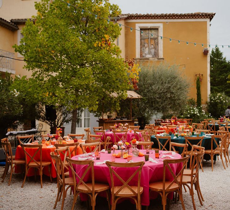 colourful wedding table decorations with pink, orange and green table cloths, taper candles and fruit centrepieces