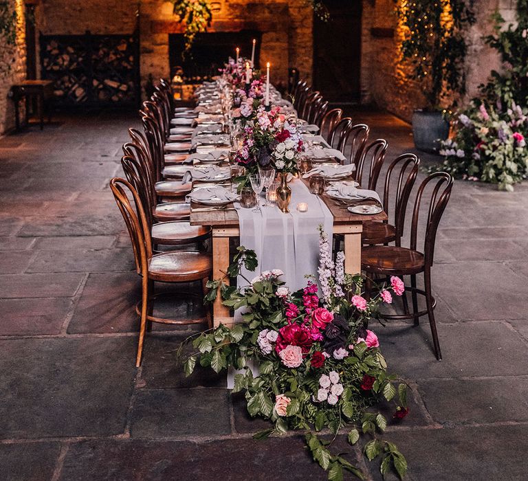 Cosy barn wedding venue lit by candlelight with intimate number of 22 guests sat for dinner 