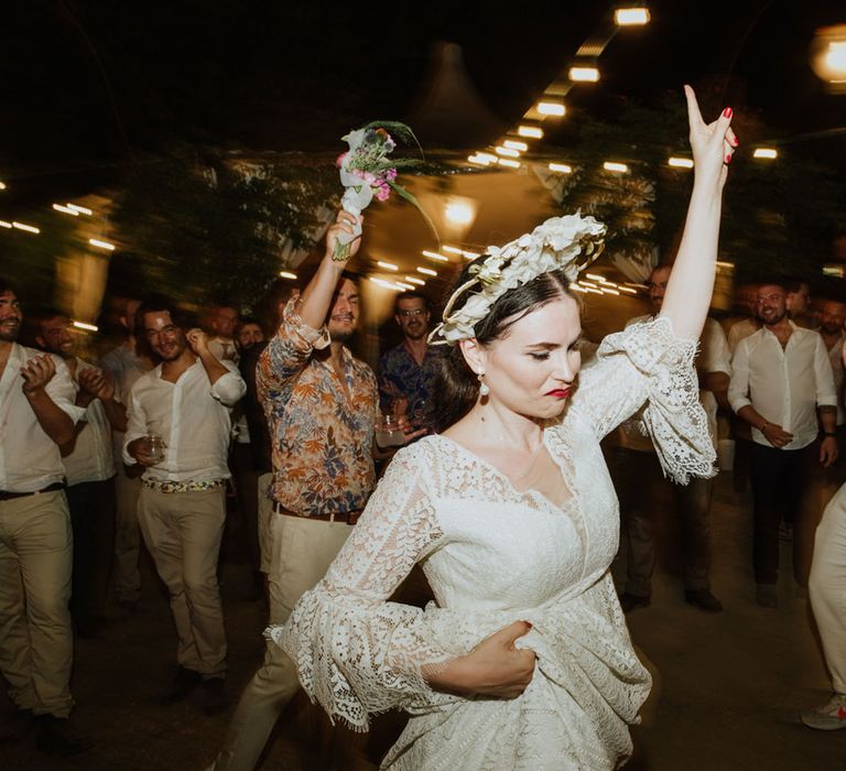 Bride in lace wedding dress, pearl earrings and bridal crown dances at wedding reception in Italy