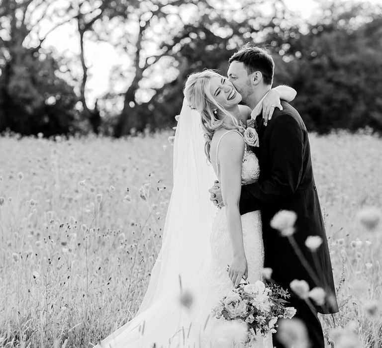 The groom kisses the bride on the cheek as she laughs for their cute couple wedding photos 