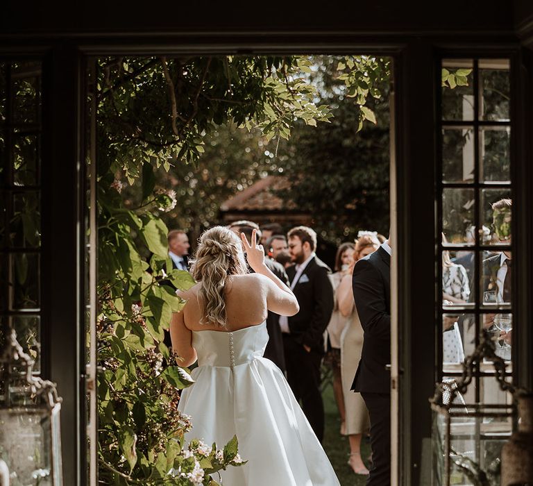 Bride in Suzanne Neville strapless wedding dress with button back detail and pleated skirt 