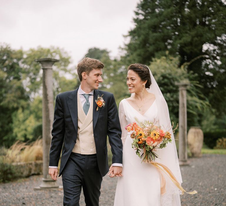 Bride wearing long sleeve wedding dress with groom in navy suit at Coombe Trenchard wedding venue 