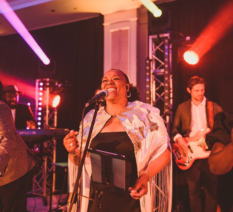 Wedding singer in sequin cape with a band playing for the wedding entertainment at the reception 