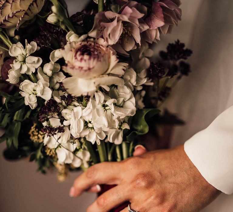 Unique engagement ring holding white and purple wedding bouquet for winter wedding at Pauntley Court