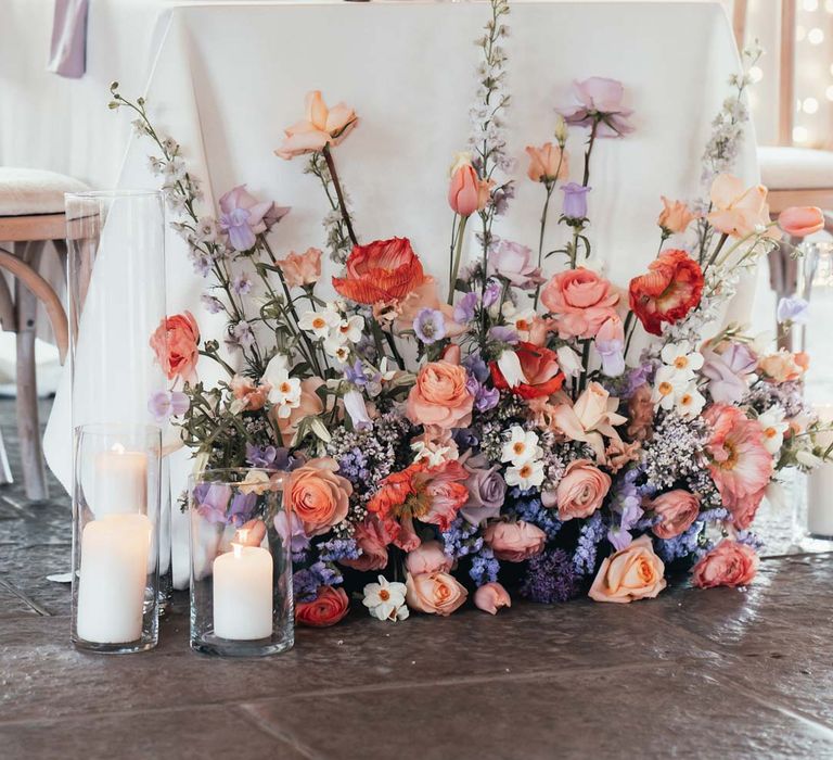 Wedding flower arrangement with peach garden roses, white peonies, lilac sweet peas, bluebells and wildflowers at Rackleys Barn