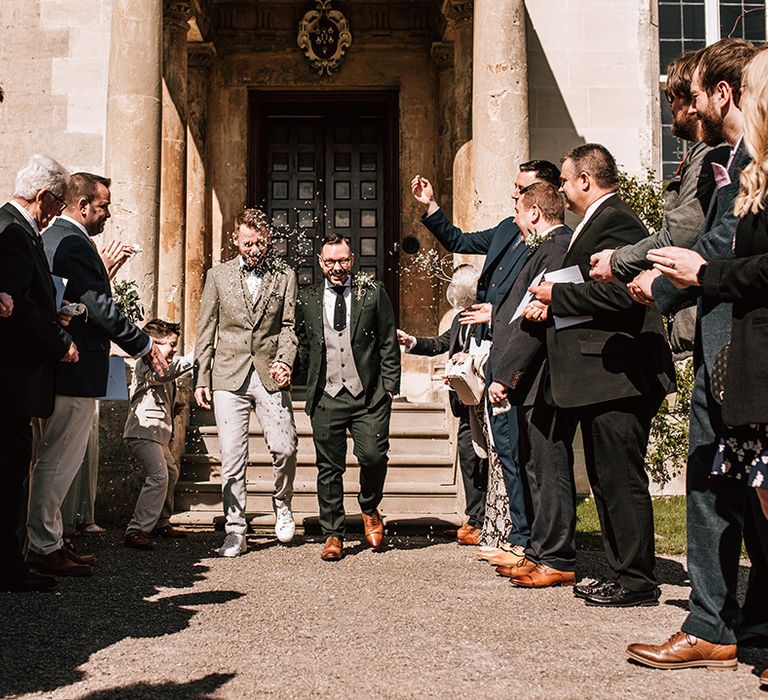 Grooms exit their wedding ceremony to a classic confetti exit at their gay wedding 