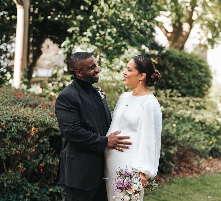 Bride with hair in a bun wearing balloon sleeve wedding dress with groom in all black suit 