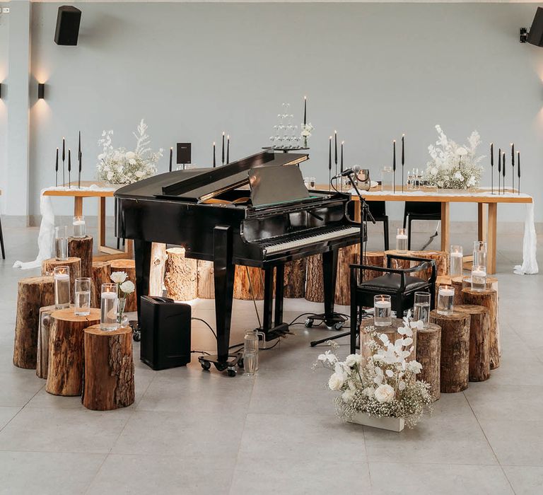 Piano surrounded by log stools and candle at Crumplebury wedding venue