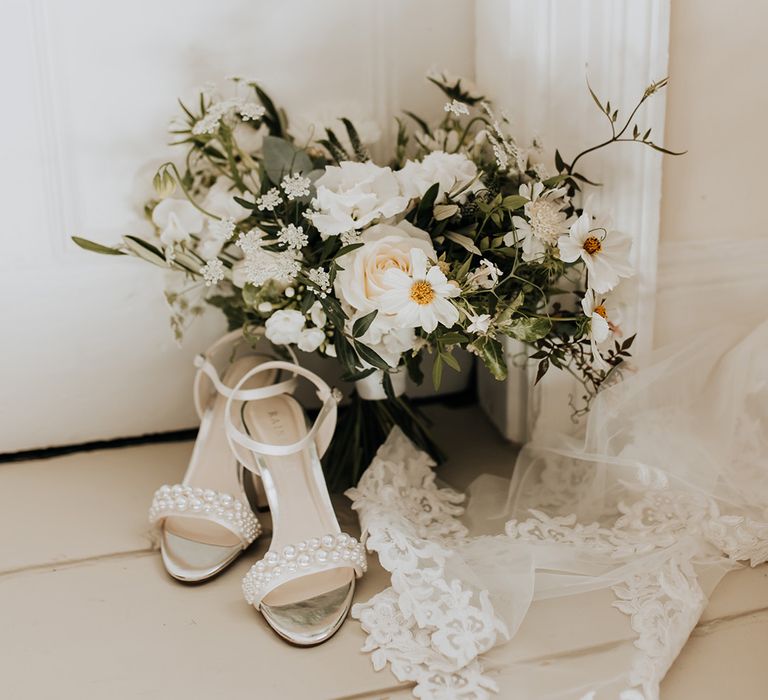 Rainbow Club pearl wedding shoes for the bride next to a white wedding bouquet 