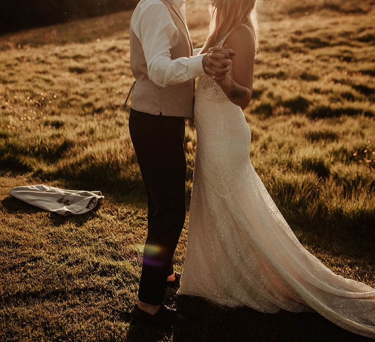 Gorgeous bride and groom posing together during the golden hour at sunset for their couple portraits