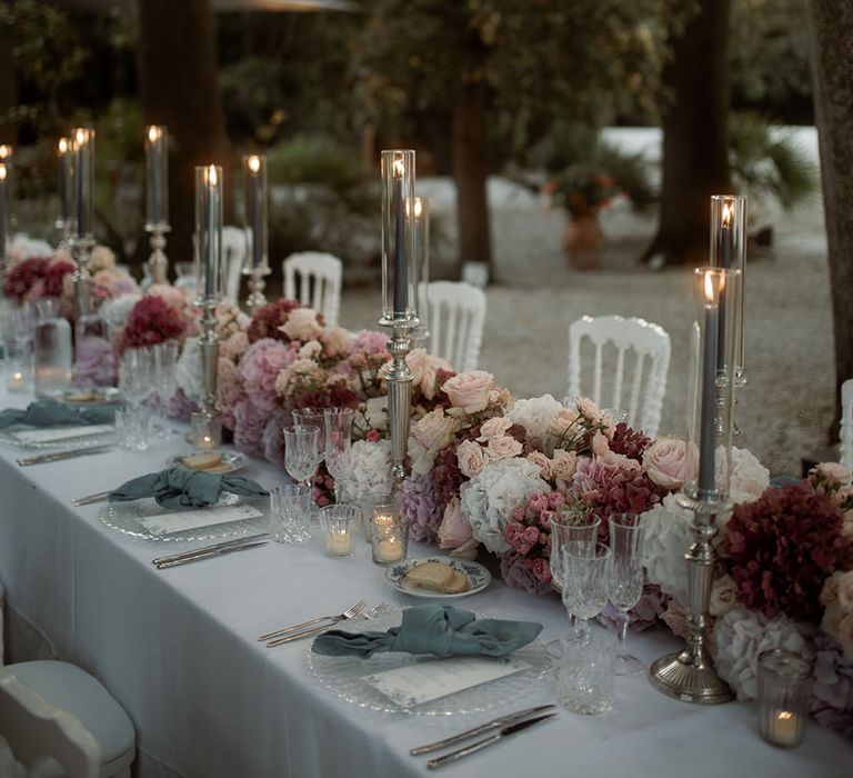 Chandeliers hang above a pastel wedding tablescape at outdoor Tuscany wedding 