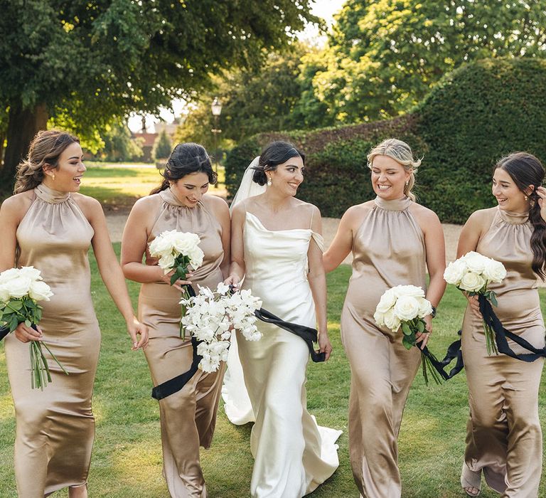 White orchid wedding bouquets held by bridesmaids in gold bridesmaid dresses 