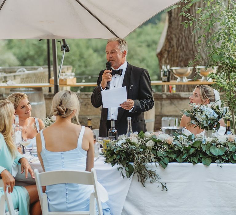 Father of the bride reading out wedding speech to the wedding guests listening 