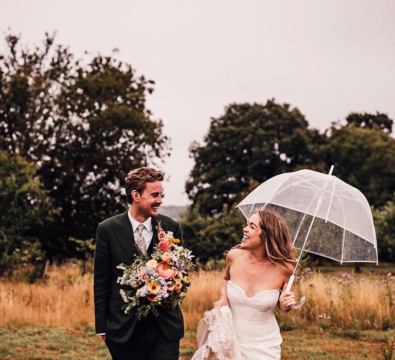 Rainy wedding day with bride in strapless wedding dress with clear umbrella 