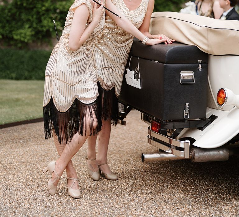 Flapper girls wedding entertainment idea with two girls in 1920 inspired gold sequin and black tassel dresses with feather headbands 