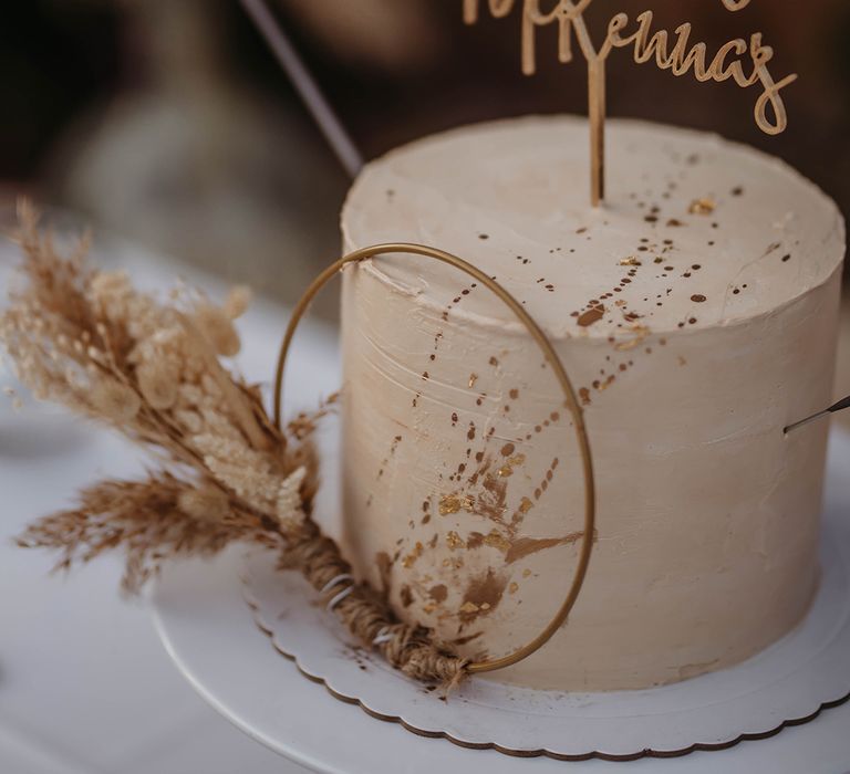 Single tiered frosted wedding cake with pampas grass decorations and personalised cake topper 