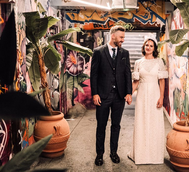 Bride and groom stand hand in hand at their wedding in London