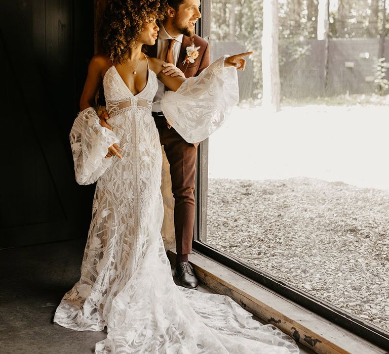 Bride in floral weding dress with detachable wedding sleeves looking out into the glass enclosures of animals 