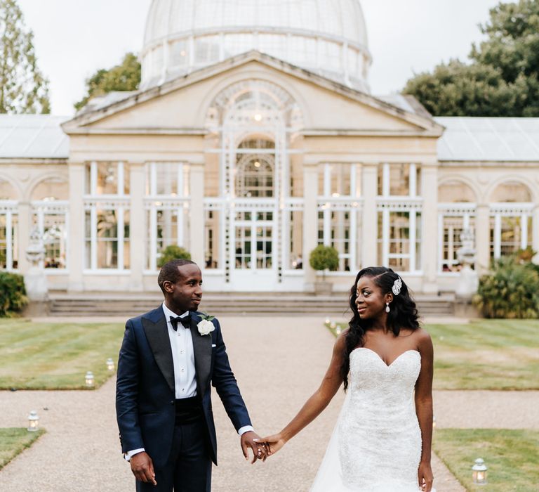 Bride and groom holding hands outside Syon Park wedding venue 