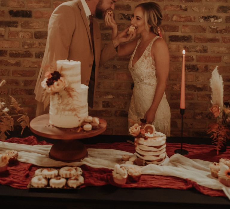 Bride and groom feeding each other wedding cake 