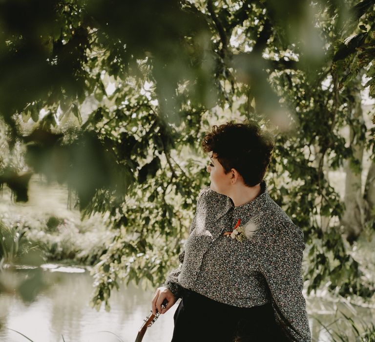 Lesbian couple sitting by the lake in a patterned shirt and jumpsuit 