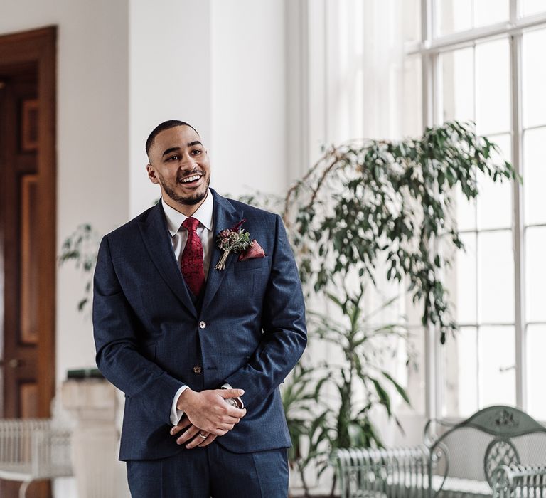 Groom in navy suit at first look wedding day moment 