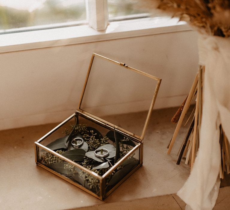 Wedding rings in glass box with dried flowers