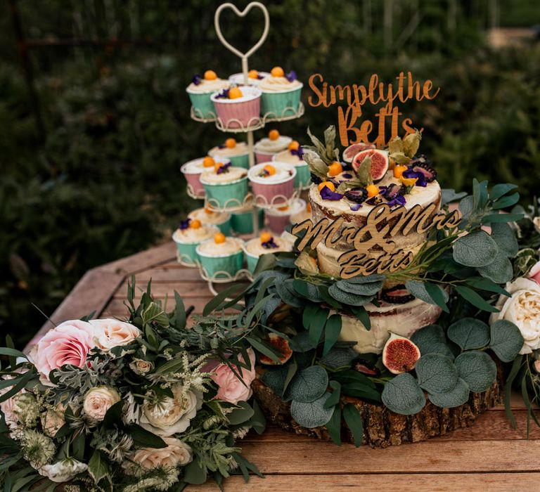 Wedding cake and cupcakes with floral foliage surrounding